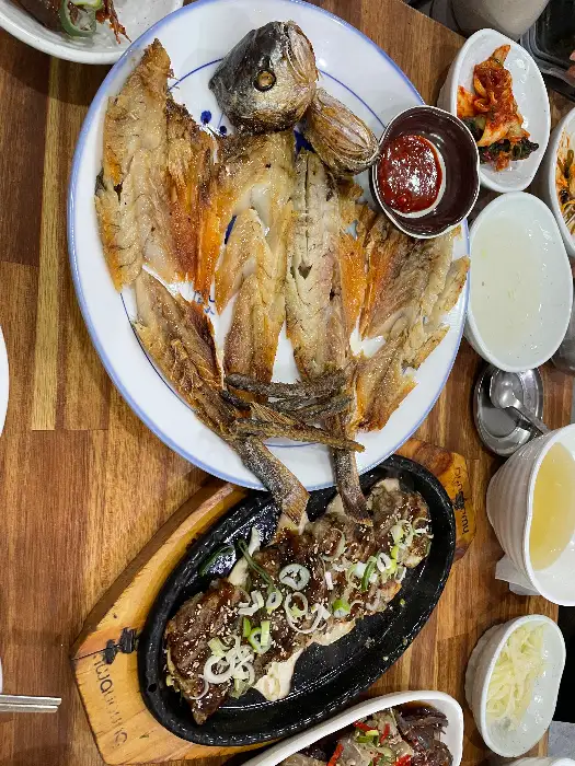 잘 차려진 한정식 상차림에서 메인 요리인 생선구이와 떡갈비, 게장 등이 보입니다.
