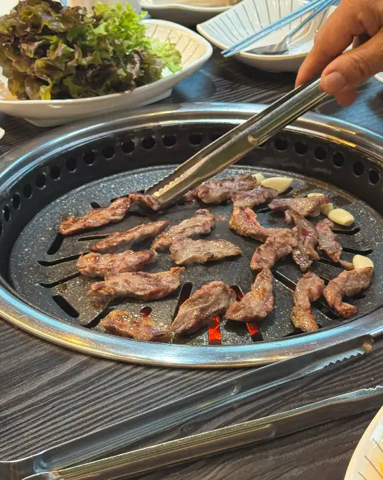 집게로 소고기를 뒤집는 손