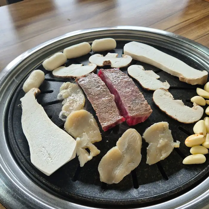 다양한 부위의 소고기와 버섯, 마늘이 함께 구워지는 모습