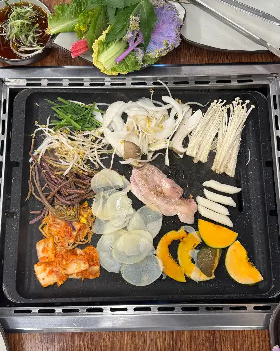 다양한 쌈 채소와 구워지는 고기, 김치, 콩나물, 버섯 등