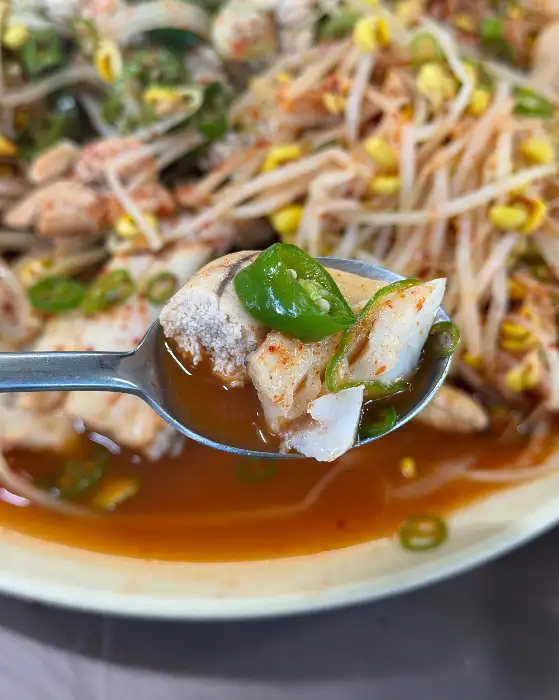 숟가락에 담긴 명태찜의 일부와 국물