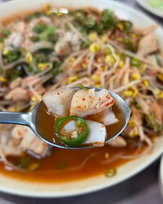 숟가락에 담긴 명태찜의 일부와 국물