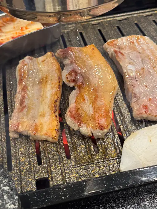불판 위에서 노릇하게 구워지고 있는 돼지고기 조각들