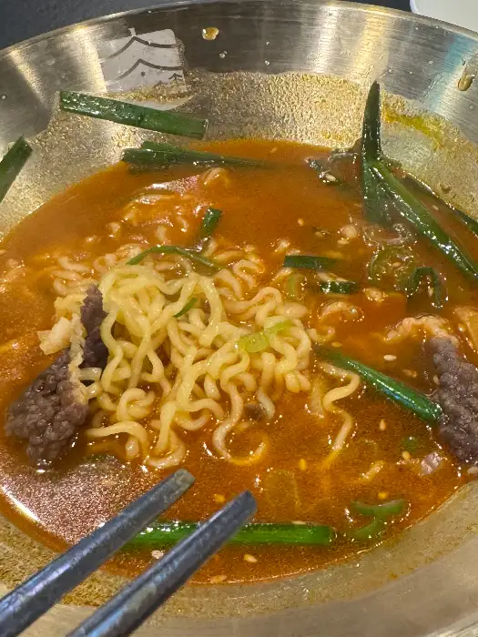 뜨끈한 국물과 함께 나오는 라면 면발과 고기 조각들