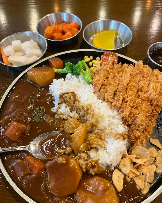 진한 카레 소스에 푹 익은 돈까스와 밥이 담긴 커리 돈까스