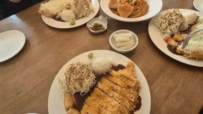 테이블 위에 여러 접시의 돈까스와 파스타가 차려져 있는 모습.
