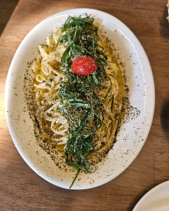 접시 중앙에 푸짐하게 쌓인 깻잎과 토마토가 올라간 파스타.