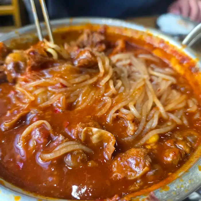 젓가락으로 갈비찜 속의 면사리와 고기를 집어 올리는 모습