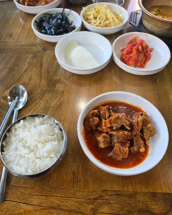 테이블에 놓인 밥 한 공기와 갈비찜, 그리고 곁들임 찬들