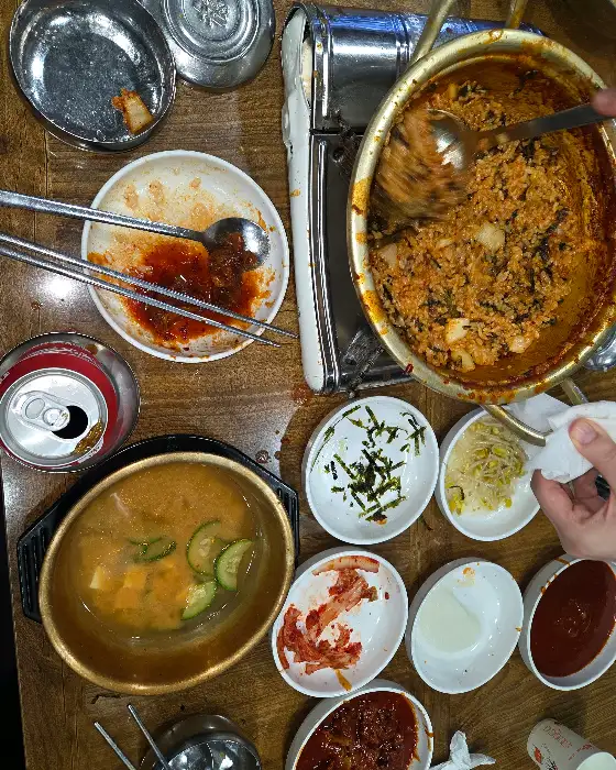 테이블에 놓인 밥, 젓가락, 숟가락, 그리고 붉은 양념이 묻은 접시