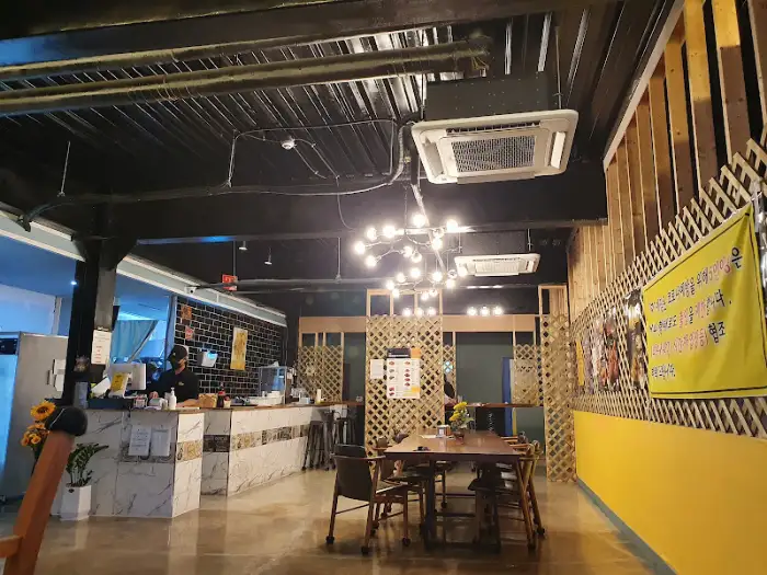 따뜻한 조명이 켜진 가게 내부 모습. 테이블과 주방이 보인다.