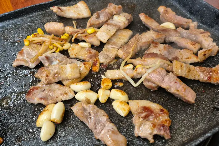불판 위에서 익어가는 삼겹살과 마늘