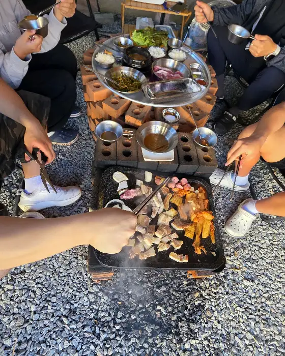 테이블에 둘러앉아 바베큐를 즐기는 사람들