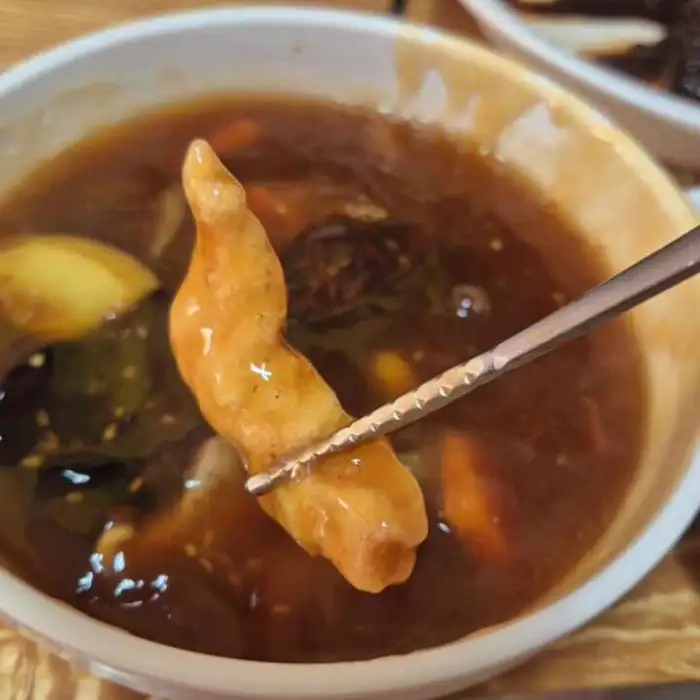 탕수육 조각을 젓가락으로 집고 있는 모습