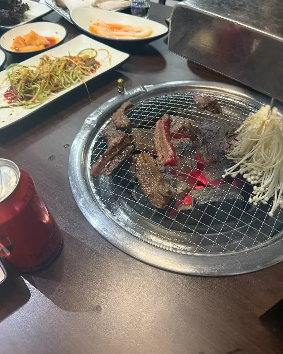 숯불 위에서 구워지고 있는 고기와 곁들임 채소