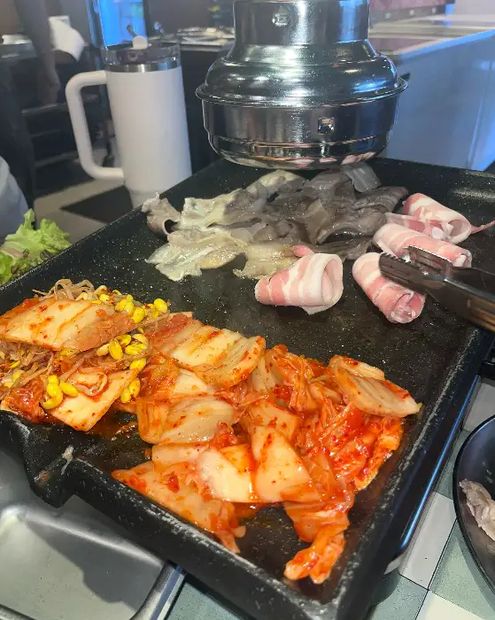 불판 위에서 익어가는 삼겹살과 김치