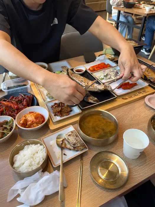 잘 구워진 생선구이 조각과 밥, 국, 반찬들