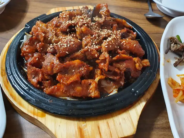 먹음직스럽게 양념된 돼지 숯불갈비가 뜨겁게 달궈진 판에 담겨 나온 모습