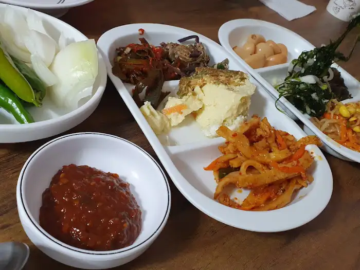 넓은 접시에 다양한 반찬들이 담겨 있고, 그 옆에 쌈 채소와 된장 등이 준비된 모습