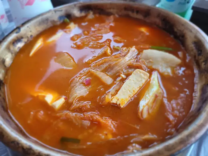 뚝배기 가득 담긴 김치찌개에 두부와 김치가 푸짐하게 들어있는 모습