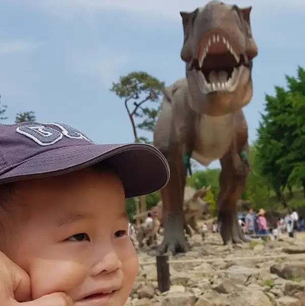 공룡 모형 앞에서 즐거워하는 아이의 모습