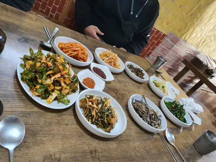 테이블 위에 놓인 다양한 나물 반찬과 밥, 찌개를 보여주는 모습