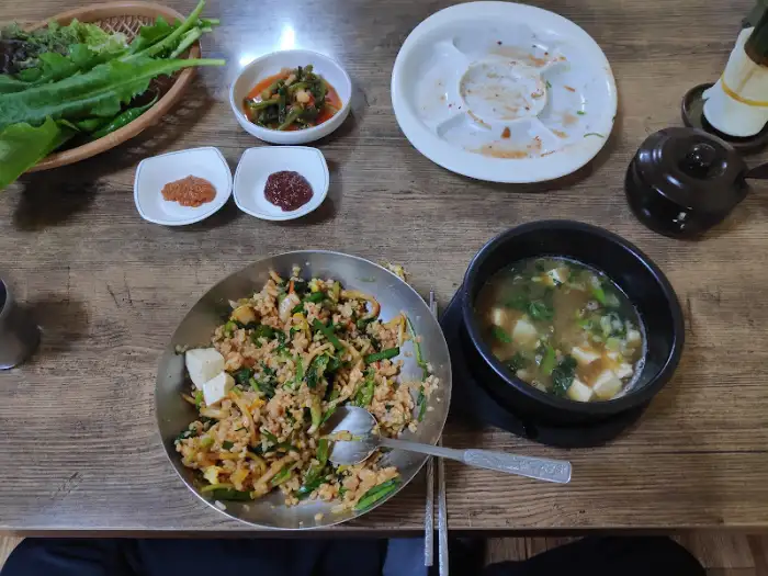 보리밥과 된장찌개가 담긴 그릇, 그리고 곁들여 나오는 나물 반찬들