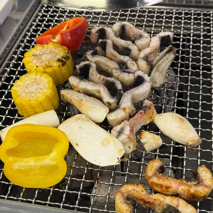 숯불 위에서 구워지고 있는 장어와 야채