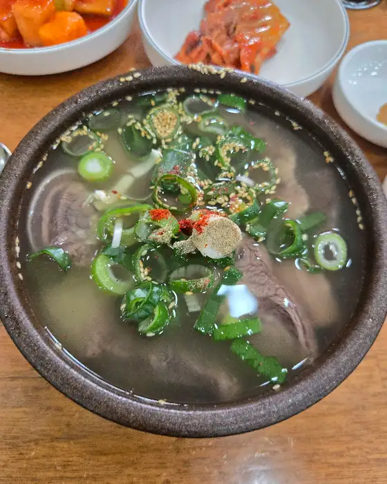 곰탕에 큼직한 고기 조각과 파, 깨가 뿌려진 모습