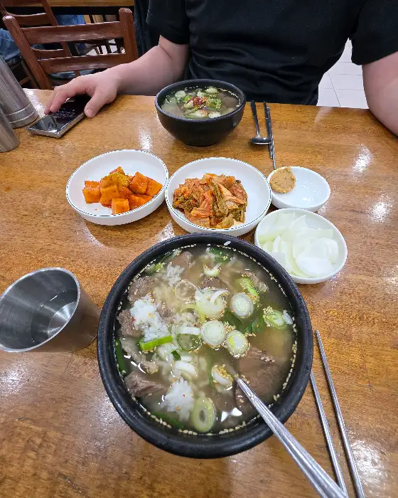 곰탕 그릇과 밥, 김치, 깍두기가 함께 담긴 모습