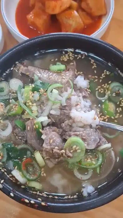 곰탕 국물에 큼직한 고기 덩어리를 숟가락으로 뜨는 모습