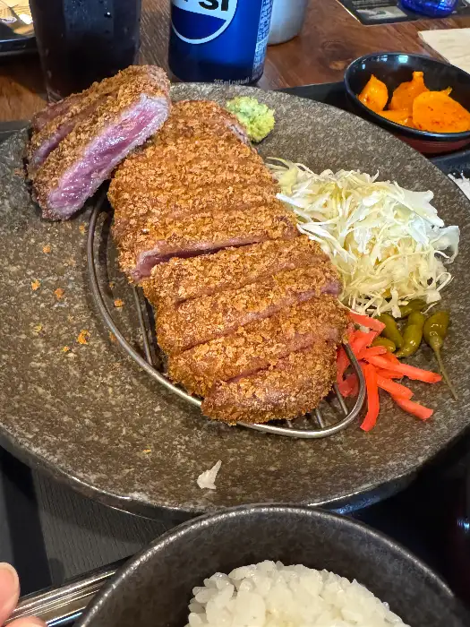 잘 튀겨진 규카츠 조각이 접시에 담겨 있고, 곁들임 반찬과 밥이 보인다.