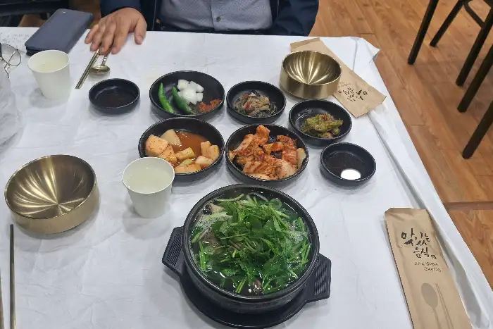 테이블 위에 정갈하게 차려진 여러 가지 반찬과 밥, 그리고 갈비탕. 놋그릇과 작은 종지들이 고급스러운 느낌을 더한다.
