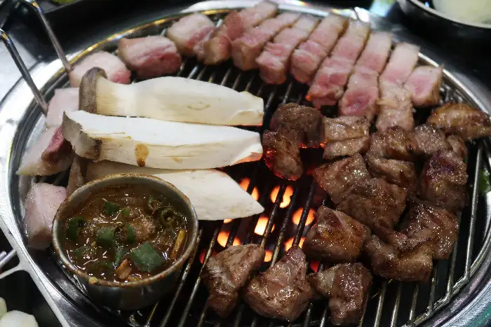 숯불 위에 구워지고 있는 삼겹살과 버섯