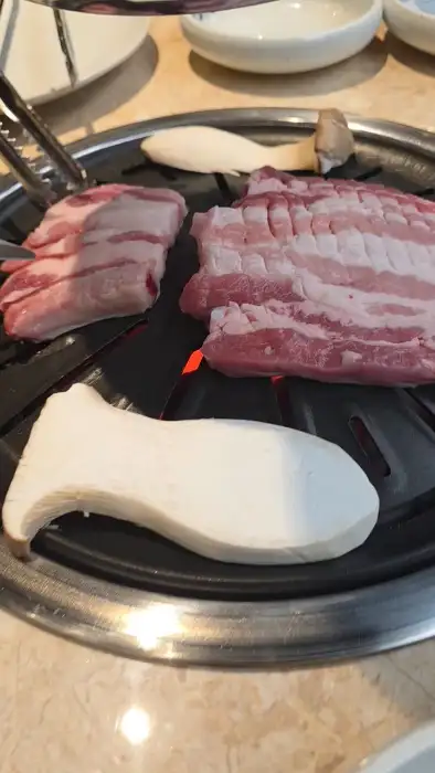 숯불 위에서 맛있게 익어가고 있는 삼겹살과 버섯