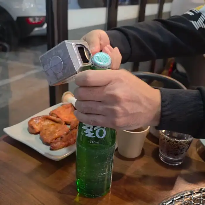 맥주병을 따고 있는 손과 숯불구이