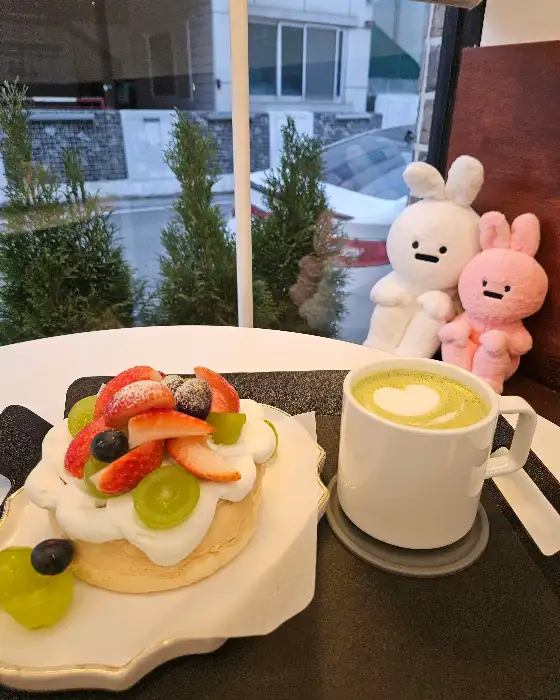 그린티 라떼와 함께 놓인 파블로바 케이크, 귀여운 토끼 인형도 보입니다.