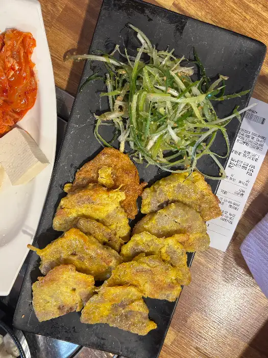 두툼하게 부쳐진 육전이 푸른 채소와 함께 접시에 담겨 있습니다.