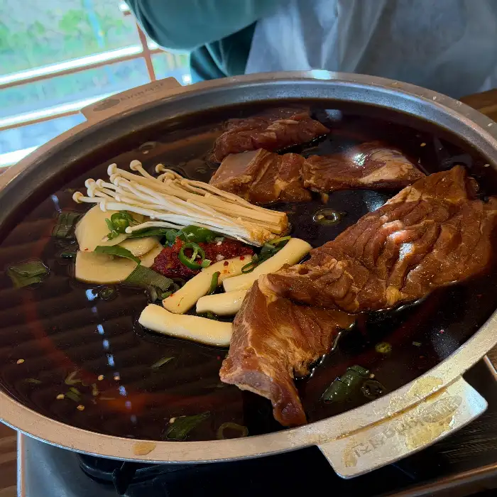 물갈비 냄비에 큼직한 갈빗대와 팽이버섯, 떡 등이 담겨 있습니다.