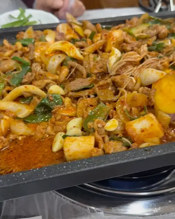 김천 능삼이네 오리주물럭 사진. 매콤한 양념에 재워진 오리고기와 각종 채소가 철판 위에서 맛있게 익어가고 있다.