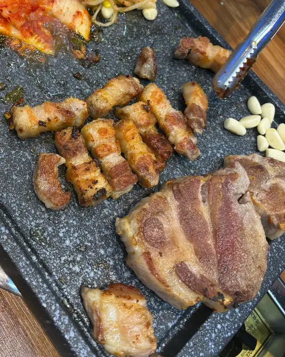 두툼한 삼겹살과 목살이 불판 위에서 맛있게 익고 있는 모습