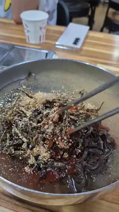 막국수에 고명을 올리고 비비는 모습