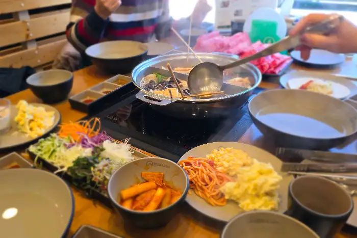 여러 사람이 둘러앉아 샤브샤브를 즐기는 모습
