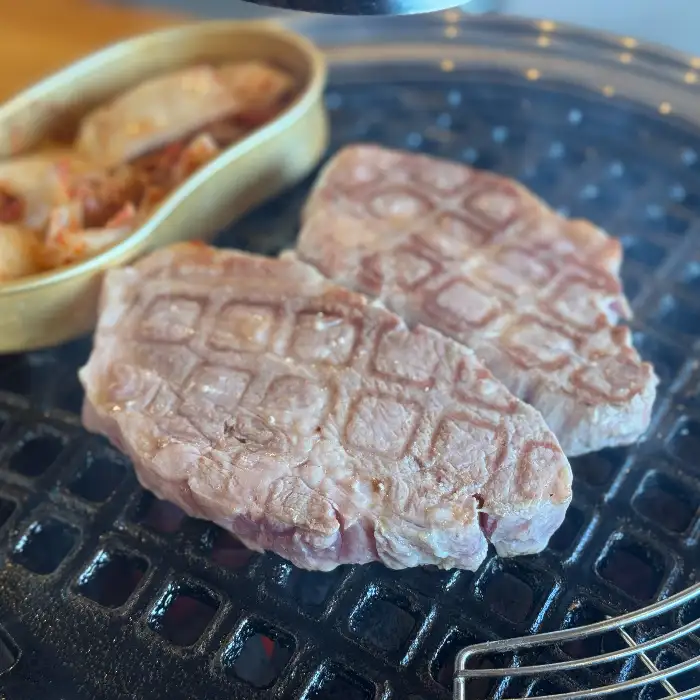 육즙 가득한 돼지고기 목살이 숯불 위에서 익어가고 있습니다.