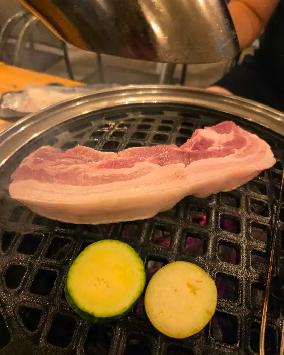 숯불 위에서 노릇하게 구워지고 있는 두툼한 삼겹살