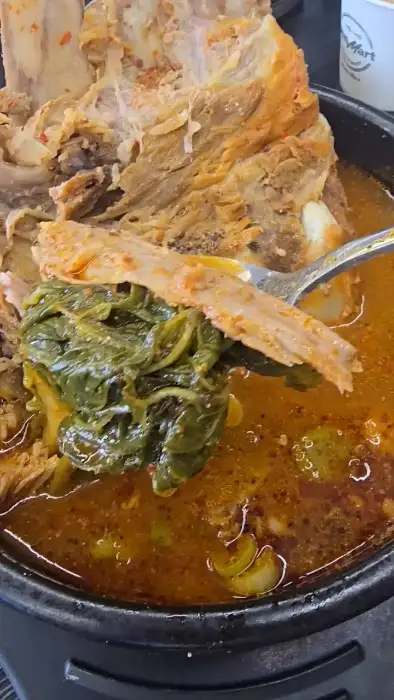 숟가락으로 뼈국의 우거지를 뜨는 모습