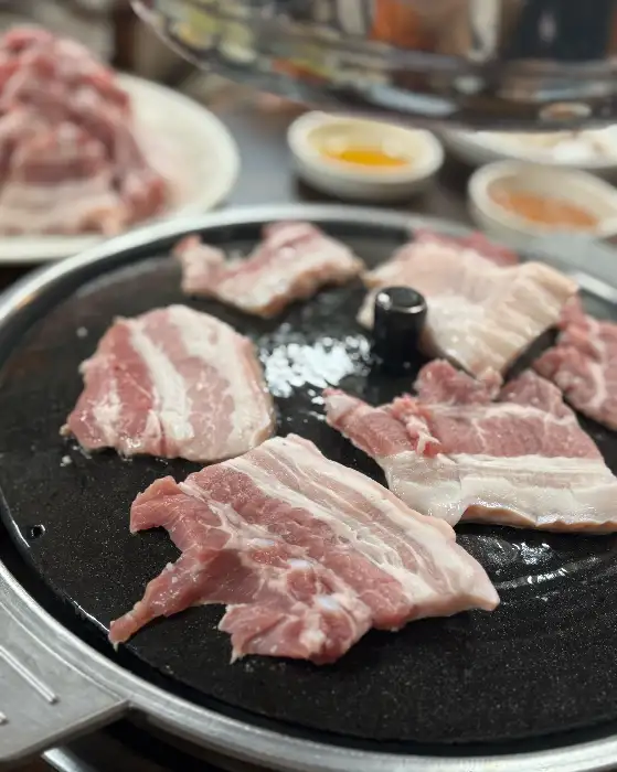 솥뚜껑 불판 위에 올려진 신선한 생삼겹살