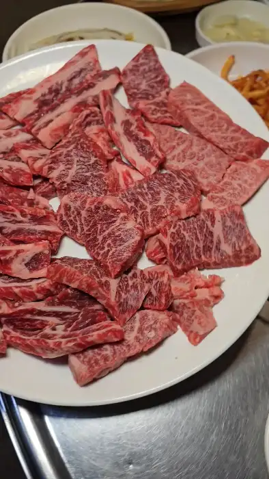 접시에 가지런히 담긴 신선한 생 소고기 조각들. 마블링이 풍부하다.
