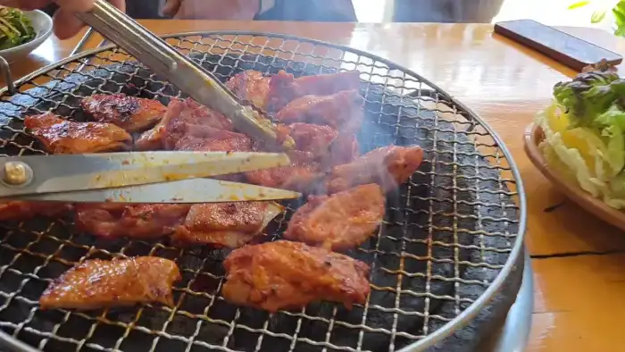 가위와 집게로 닭갈비를 자르는 모습