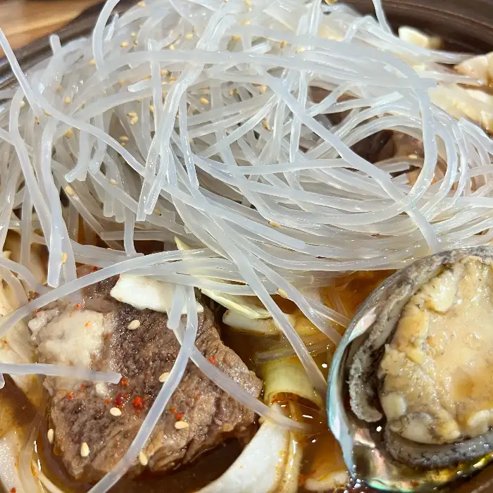 전복과 소갈비의 클로즈업 - 신선한 전복의 모습과 부드러워 보이는 소갈비 조각이 보입니다.